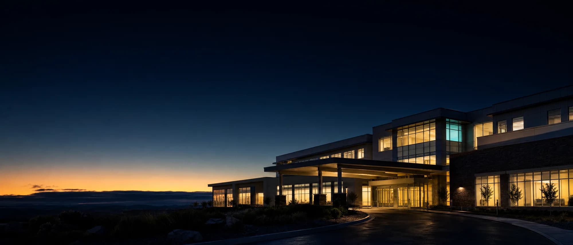 A healthcare building at first light, glowing softly from within.